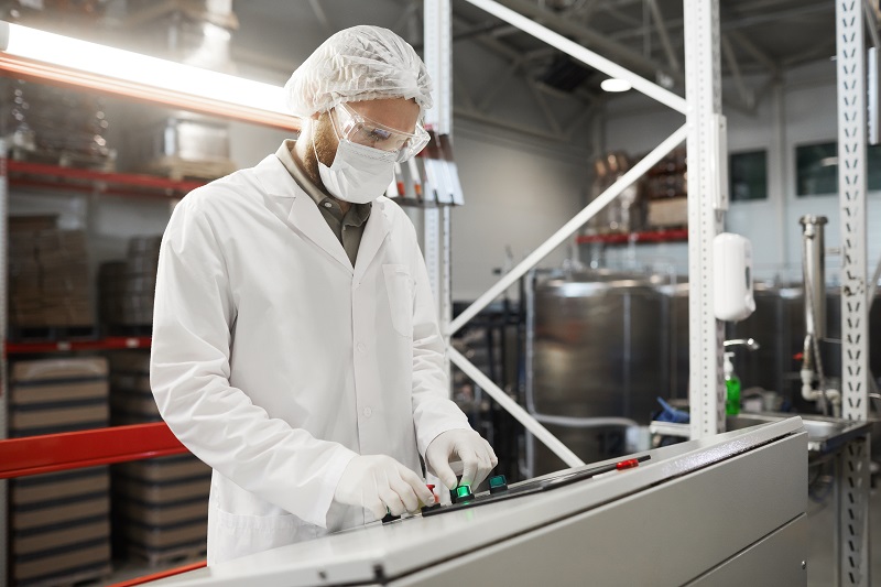 Male Worker Pressing Buttons on Control Panel at Factory